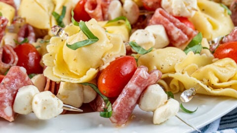 Close up of a single tortellini skewer on a platter full of this delicious and colorful appetizer.