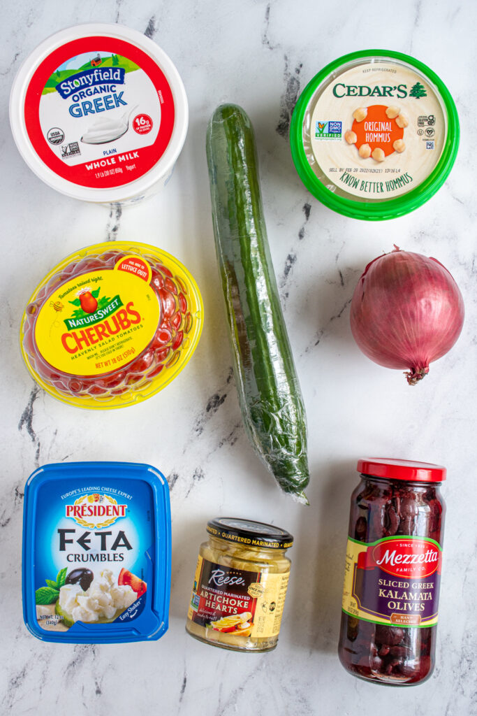 Ingredients for Greek Layer Dip laid out on a tabletop.