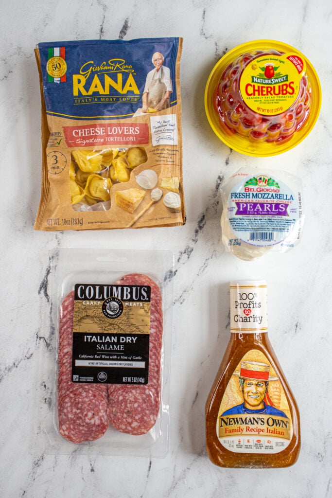The five ingredients needed to make tortellini skewers laid out on a table.