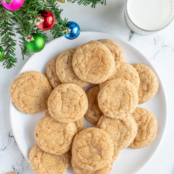 Overhead view of a plate full of eggnog snickerdoodles showing off a cinnamon and nutmeg outside.