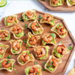 Pinterest Pin with text 'Guacamole Shrimp Bites', image of a wood platter filled with many shrimp guacamole bites.