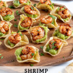 Pinterest Pin with text 'Guacamole Shrimp Bites', image of a wood platter filled with many shrimp guacamole bites.