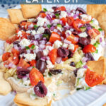 Pinterest Pin with text 'Greek Layer Dip', image of a platter filled with Greek Layered Dip and pita chips.