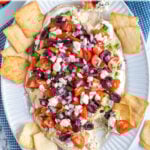 Pinterest Pin with text 'Greek Layer Dip', image of a platter filled with Greek Layered Dip and pita chips.