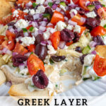 Pinterest Pin with text 'Greek Layer Dip', image of a platter filled with Greek Layered Dip and pita chips.