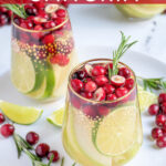Pinterest Pin with text 'White Christmas Sangria', image of stemless wine glasses filled with White Christmas sangria, pears, limes, and cranberries.