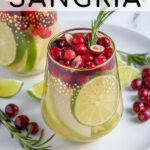 Pinterest Pin with text 'White Christmas Sangria', image of stemless wine glasses filled with White Christmas sangria, pears, limes, and cranberries.