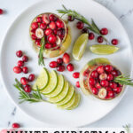 Pinterest Pin with text 'White Christmas Sangria', image of stemless wine glasses filled with White Christmas sangria, pears, limes, and cranberries.