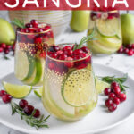Pinterest Pin with text 'White Christmas Sangria', image of stemless wine glasses filled with White Christmas sangria, pears, limes, and cranberries.