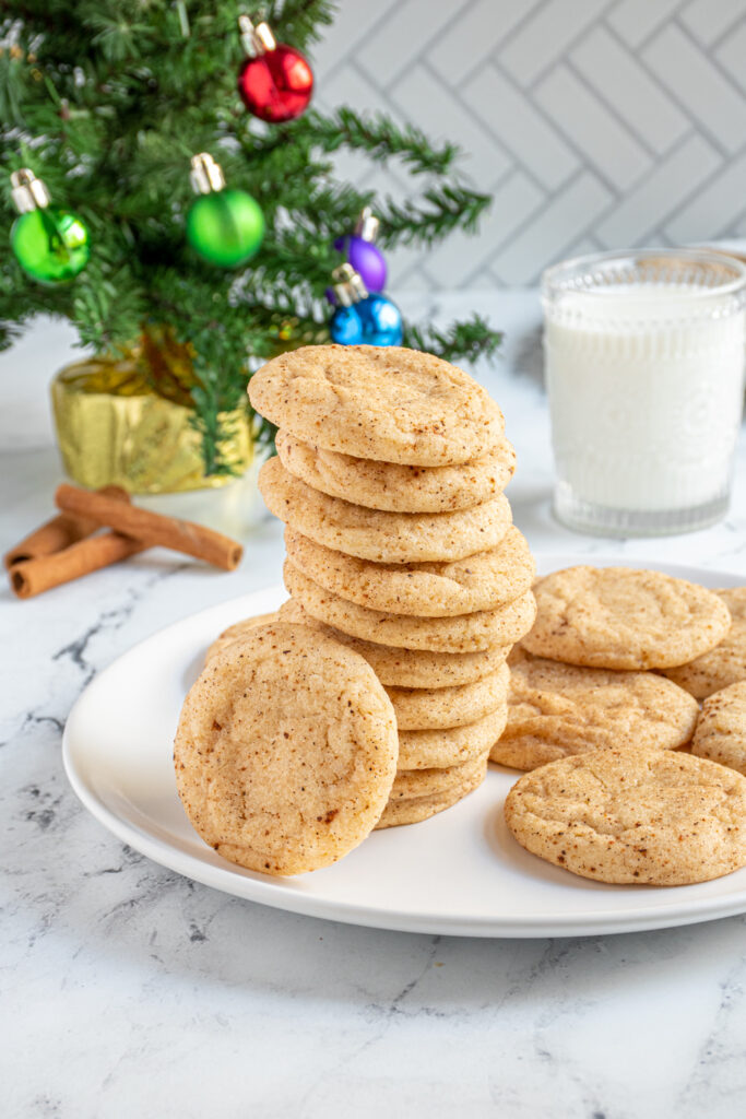 A tall stack of eggnog snickerdoodles on a plate with a cookie leaning against the stack.