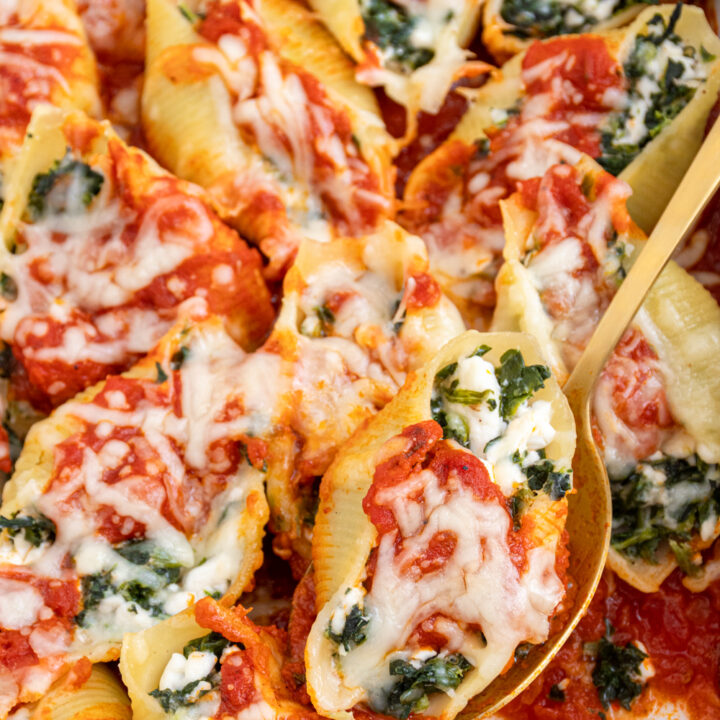 Close up of a spinach stuffed shell without ricotta on a serving spoon showing off spinach, cottage cheese, and sauce.