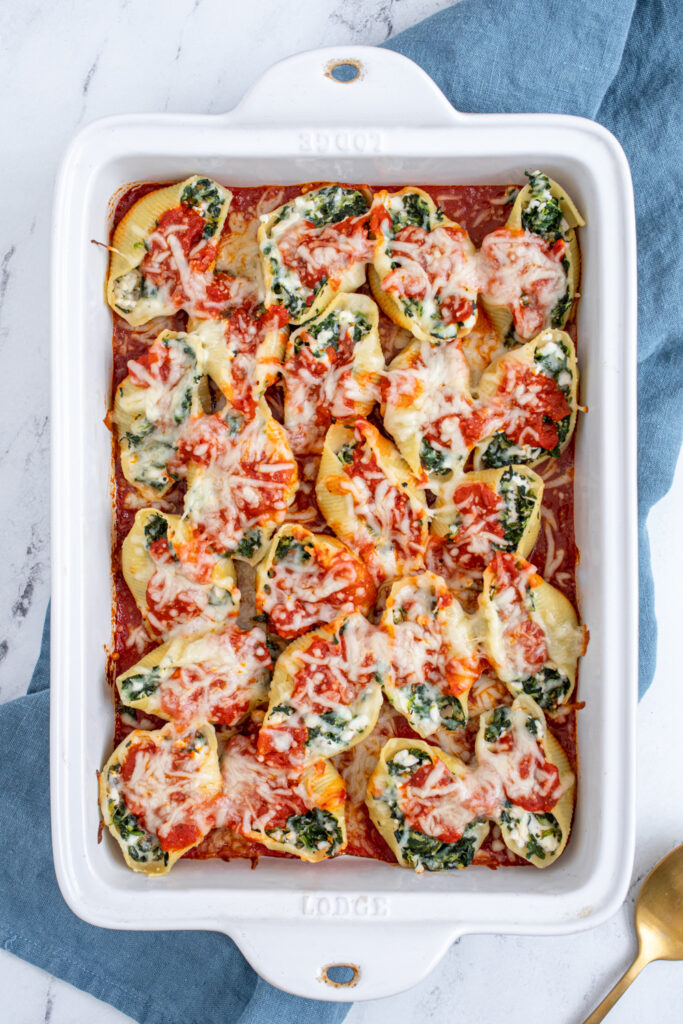 Overhead view of freshly cooked spinach stuffed shells in a dish.