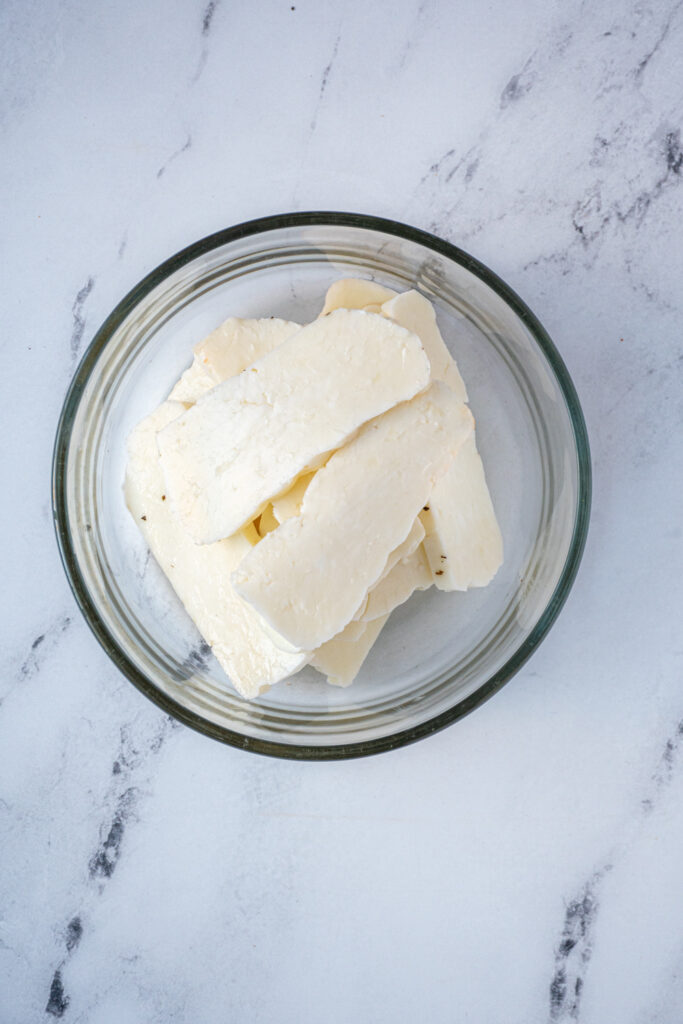 A small bowl filled with slices of halloumi cheese.