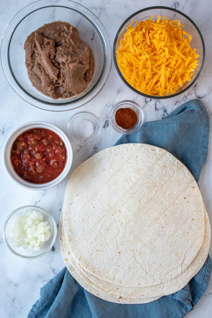 Ingredients needed to make refried bean burritos laid out on a table top.
