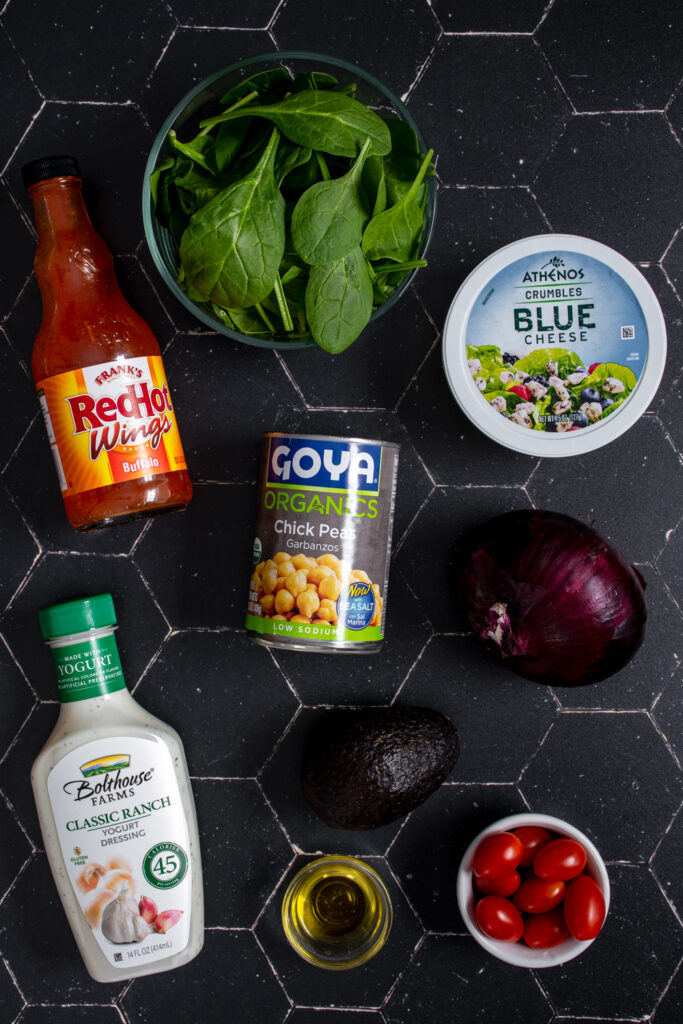 Ingredients for buffalo chickpea salad laid out on a black tabletop.