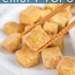 Pinterest pin with text 'Air Fryer Crispy Tofu', image of a golden brown piece of tofu being held by chopsticks.