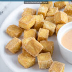 Pinterest pin with text 'Air Fryer Crispy Tofu', image of a golden brown pile of tofu on a white plate.