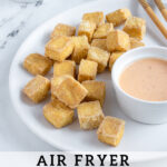 Pinterest pin with text 'Air Fryer Crispy Tofu', image of a golden brown pile of tofu on a white plate.