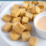 Pinterest pin with text 'Air Fryer Crispy Tofu', image of a golden brown pile of tofu on a white plate.