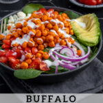 Pinterest Pin with text 'Buffalo Chickpea Salad', image of a brightly colored buffalo chickpea salad in a black bowl.