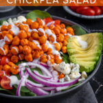 Pinterest Pin with text 'Buffalo Chickpea Salad', image of a brightly colored buffalo chickpea salad in a black bowl.