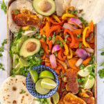 Pinterest Pin with text 'Vegetarian Halloumi Fajitas', image with a tray full of fajita veggies and golden brown halloumi cheese.