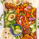 Pinterest Pin with text 'Halloumi Fajitas', image with a tray full of fajita veggies and golden brown halloumi cheese.