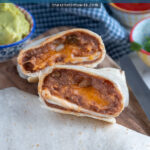 Pinterest Pin with text 'Cheesy Refried Bean Burrito', with image of two halves of a burrito cut open to reveal the inside on a cutting board.