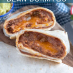 Pinterest Pin with text 'Quick & Easy Cheesy Refried Bean Burrito', with image of two halves of a burrito cut open to reveal the inside on a cutting board.