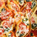 Pinterest pin with text 'Spinach Stuffed Shells without Ricotta', image of sauce and cheesy stuffed shells in a white casserole dish.