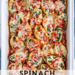 Pinterest pin with text 'Spinach Stuffed Shells without Ricotta', image of sauce and cheesy stuffed shells in a white casserole dish.