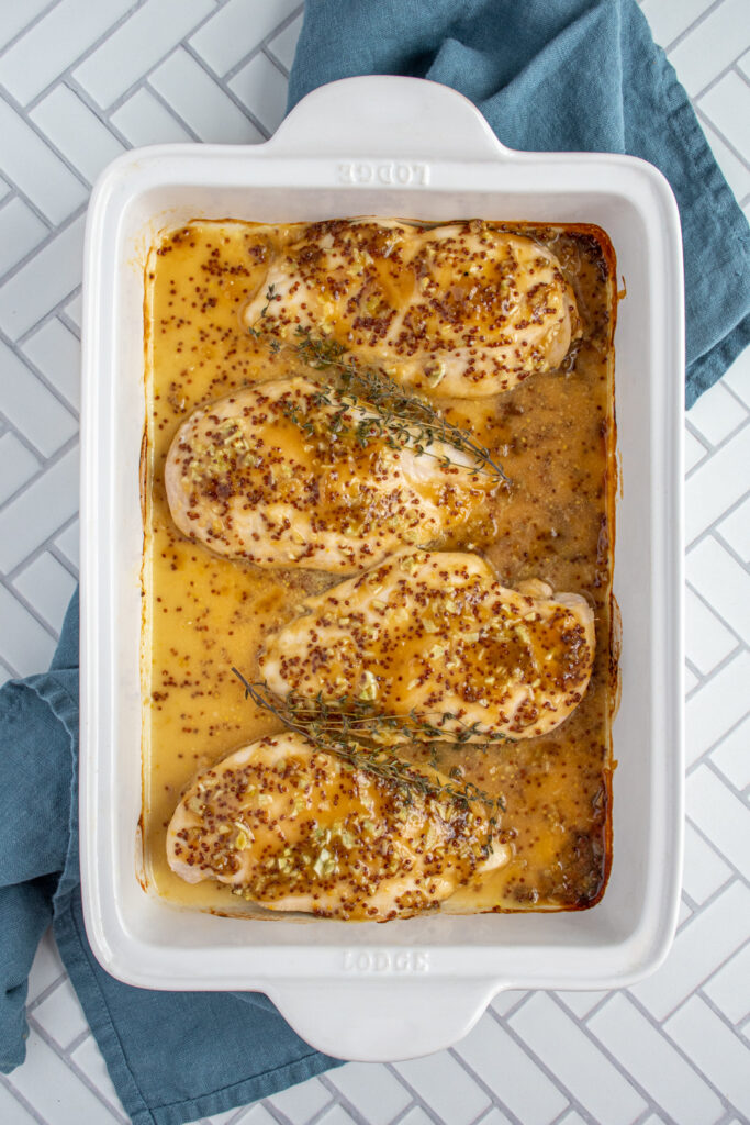 A white baking dish showing the fully cooked honey mustard chicken.