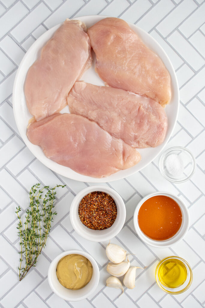Ingredients needed to make baked honey mustard chicken breasts laid out on a table top.