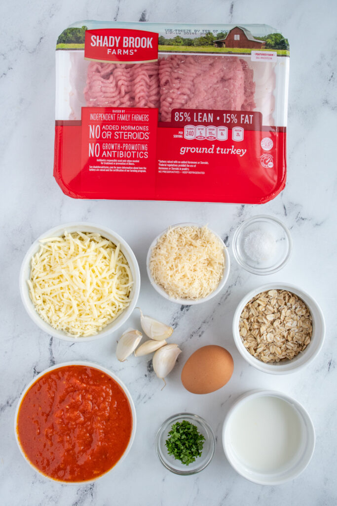 Ingredients needed laid out on a tabletop to make turkey meatballs baked in tomato sauce.