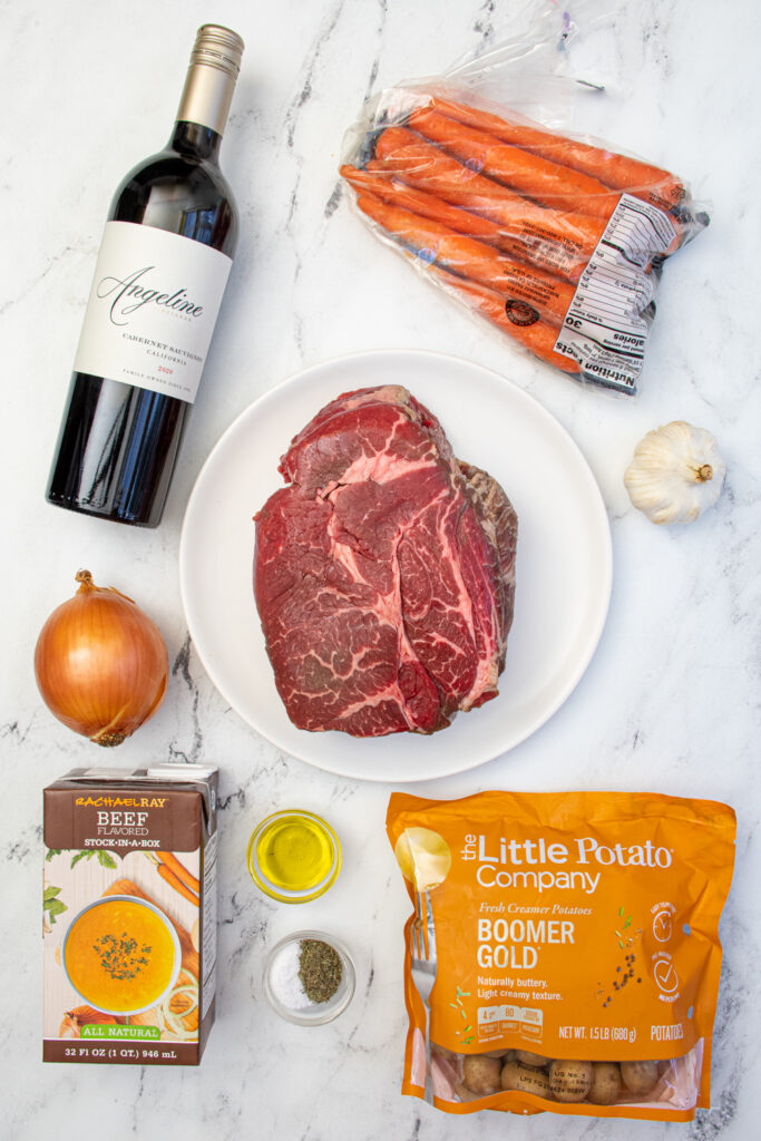 All the ingredients needed to make crockpot pot roast with red wine laid out on a table top.