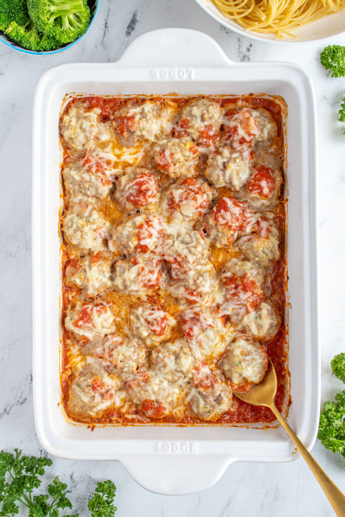 Overhead view of a white casserole dish filled with baked turkey meatballs covered in Mozzarella cheese.