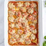 Pinterest Pin with text overlay 'Baked Turkey Meatballs', image of baked turkey meatballs covered in cheese in a casserole dish.