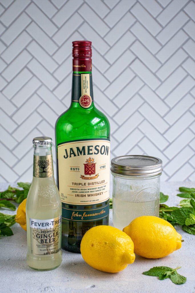 Ingredients needed to make an Irish Lemonade including Jameson Whiskey, Ginger beer, simple syrup, and fresh lemons.