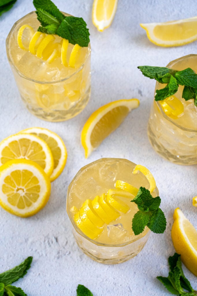 Overhead view of the Irish Lemonade cocktail in whiskey glasses garnished with lemon peel and mint leaves.