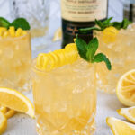 Pinterest Pin with text overlay 'Irish Lemonade', image of whiskey glass filled with ice and Irish lemonade garnished with lemon peel and mint.