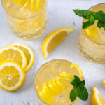 Pinterest Pin with text overlay 'Irish Lemonade', image of whiskey glass filled with ice and Irish lemonade garnished with lemon peel and mint.