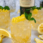 Pinterest Pin with text overlay 'Irish Lemonade', image of whiskey glass filled with ice and Irish lemonade garnished with lemon peel and mint.