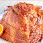 Pinterest pin with text 'Orange Bourbon Glazed Ham', images of glazed ham with oranges on a platter.