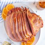 Pinterest pin with text 'Orange Bourbon Glazed Ham', images of glazed ham with oranges on a platter.