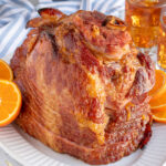 Pinterest pin with text 'Orange Bourbon Glazed Ham', images of glazed ham with oranges on a platter.