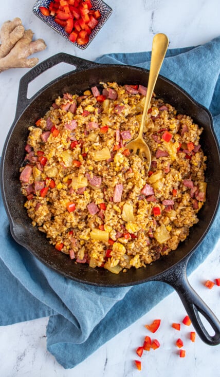 Overhead view of a skillet filled with ham fried rice with pineapples and red bell pepper.