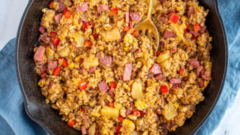 Overhead view of a skillet filled with ham fried rice with pineapples and red bell pepper.