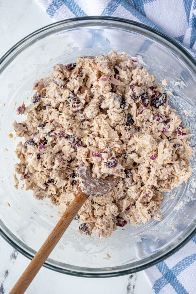 Close up of just mixed tuna salad with cranberries in a glass bowl with a spoon.
