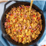 Pinterest pin with text 'Ham Fried Rice with Pineapple', image of black skillet with fried rice and a serving spoon.