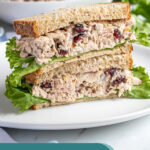Pinterest Pin with text overlay 'Tuna Salad with Cranberries', image of two halves of a sandwich stacked revealing the no celery tuna salad.